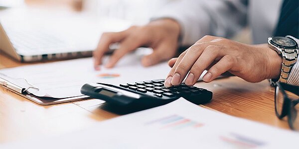 Digitaler Einkaufsprozess, Hände prüfen Unterlagen mit Taschenrechner.