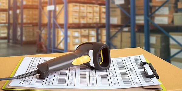 Barcode-Scanner auf einem Stapel mit Listen und Etiketten - E-Procurement im Mobil-Bereich.